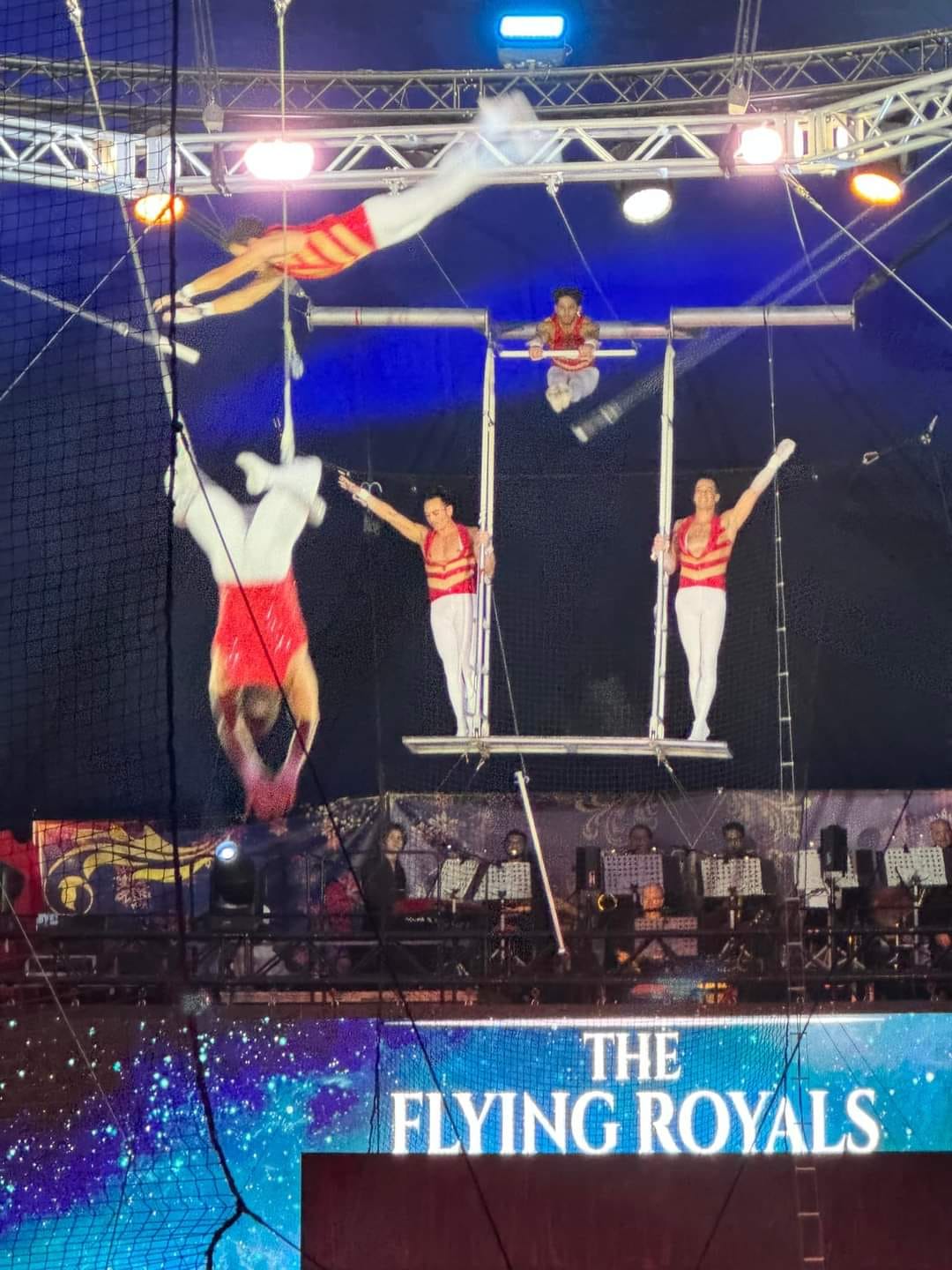 Multiple Flying Royals performers in a live production with musicians below