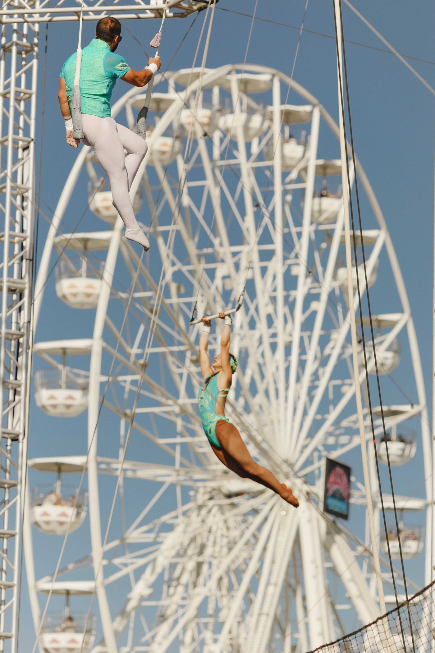 Flying Royals performers framed by a ferris wheel at a fair